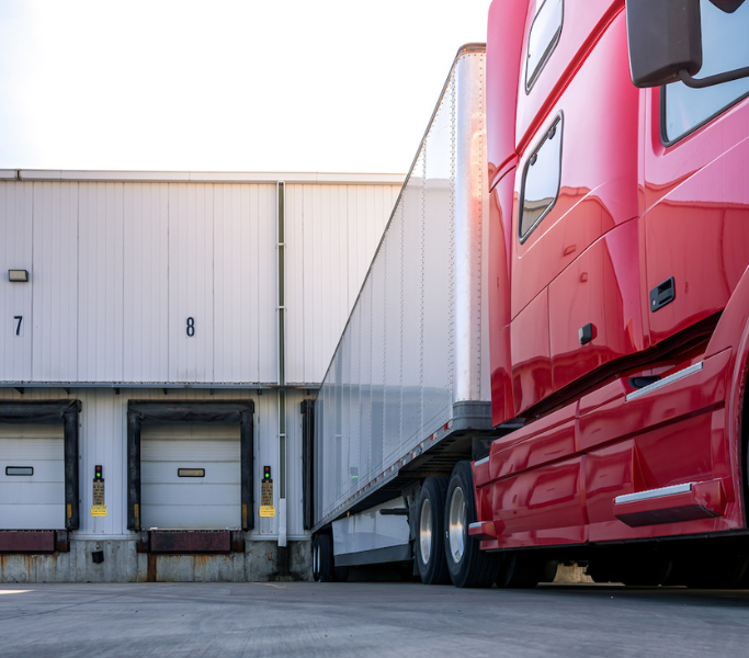 Truck parked at a loading dock, with the trailer door open and ready for loading or unloading
